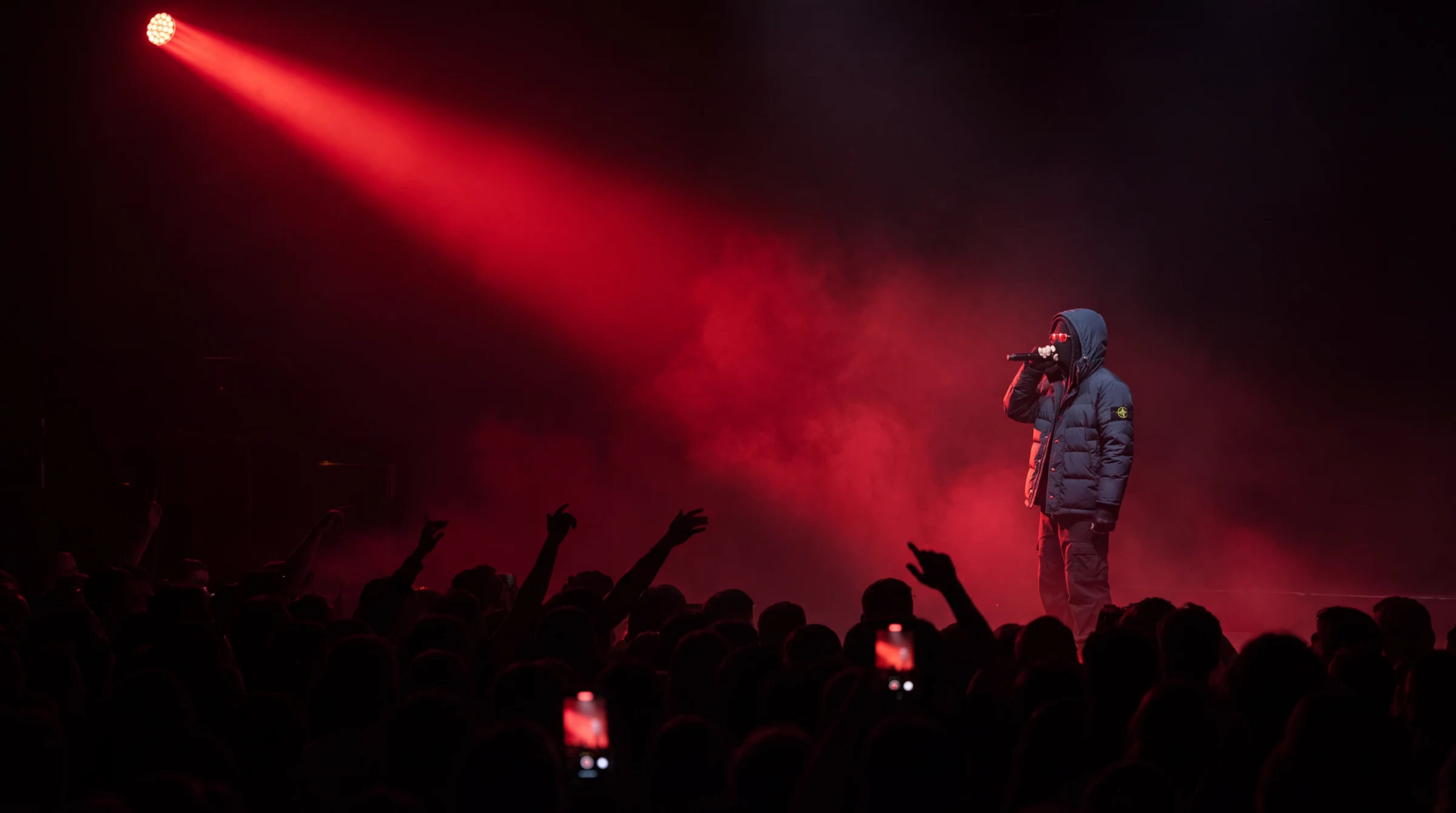 LOVIXX on stage under a red spotlight, crowd in the foreground